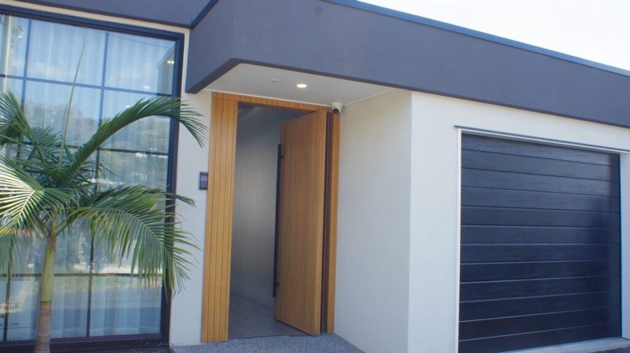 Entrance of a completed co-living property with a timber pivot door and palm tree